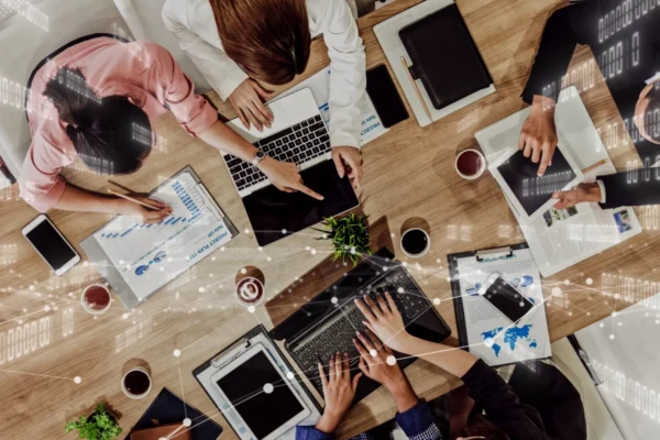 A group of people sitting around a table with laptops.
