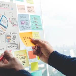 A person writing on post it notes on a board