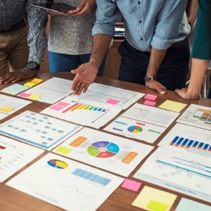 A group of people standing around a table with papers.