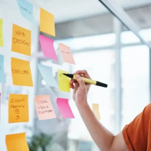 A person writing on post it notes on a wall.